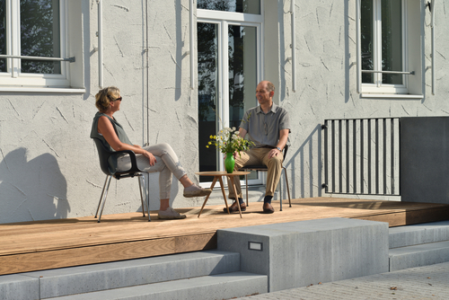 Zwei Patienten sitzen in der Sonne auf der Terrasse und unterhalten sich in entspannter Atmosphäre.