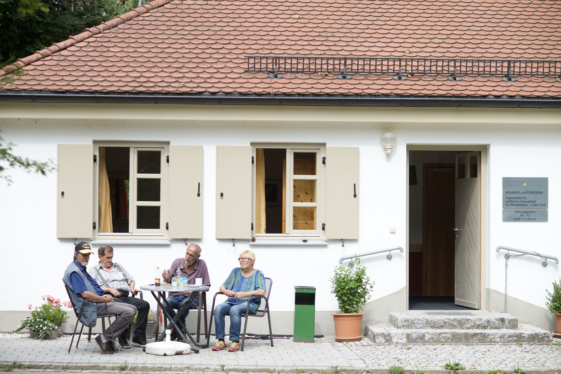 Patienten sitzen zusammen vor dem Cafe Dora am Roesslehaus.